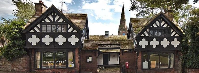 The club's black-and-white timbered frontage by day, with the Village Club sign over the entrance